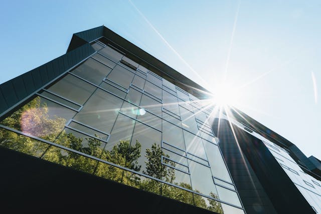 Multi-story building reflecting the sun and trees